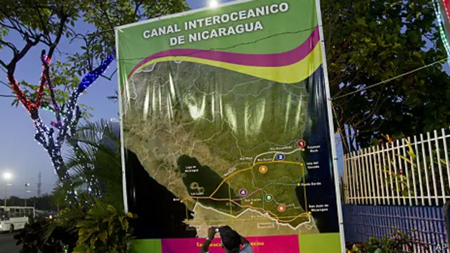 尼加拉瓜首都马拉瓜一名工人在大运河宣传计划海报前拍照（4/12/2013）