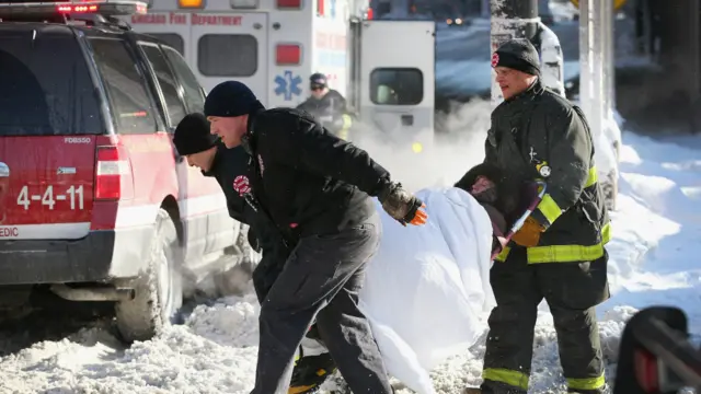 شکاگو میں آگ بجھانے والے عملے کے ارکان ایک زخمی خاتون کو ایمبولینس میں منتقل کر رہے ہیں