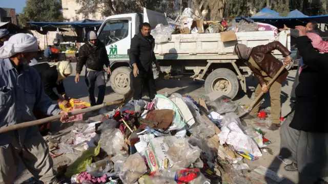 عمال جمع قمامة يقومون بازالة القمامة التي تكدست في شوارع الفلوجة.