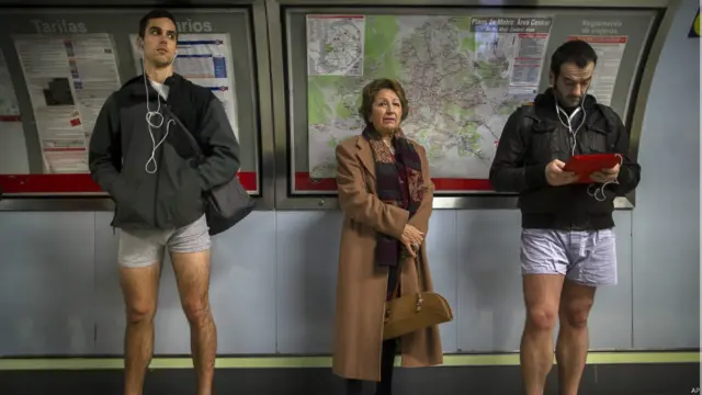 Пассажир в обычной одежде между участниками акции "день без штанов"