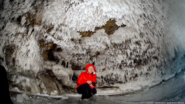 बैकल झील का बर्फ की गुफा के भीतर एक महिला. ऐंड्रे नेकरासोव