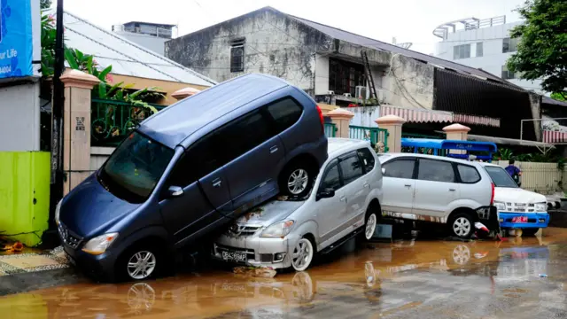 Banjir bandang meninggalkan mobil-mobil bertumpukkan
