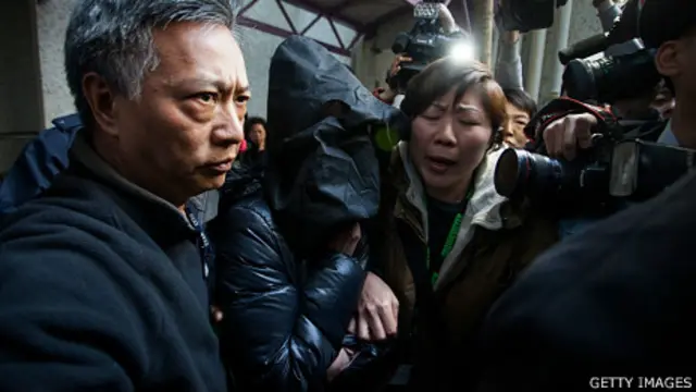 虐待女佣案嫌疑人罗允彤（中）被警员蒙头带回香港将军澳住所调查（21/1/2014）