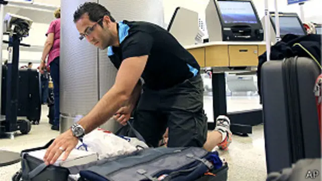 turista revisa maletas en aeropuerto de EEUU