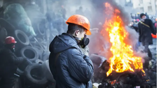 معترضان در نزدیکی استادیوم داینامو در کی‌یف در حال آتش زدن لاستیک های خودرو.