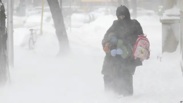 Pejalan kaki berusaha berjalan melawan tiupan salju di Chicago, Illinois