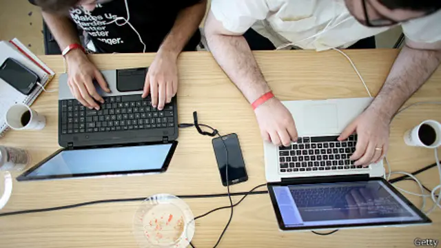 Dos hombres usando computadoras portátiles.