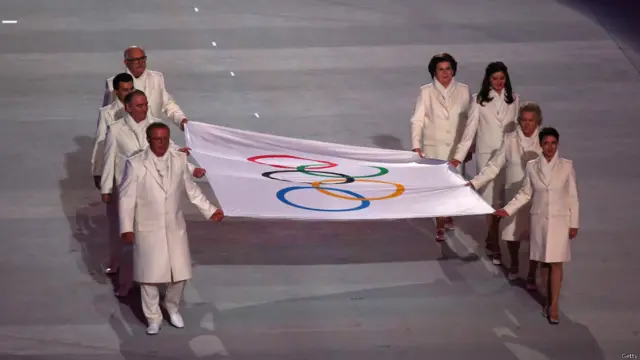 Обязательная часть любой церемонии открытия Олимпийских игр - поднятие олимпийского флага. Его внесли на арену двукратный олимпийский чемпион Вячеслав Фетисов, шестикратная чемпионка Лидия Скобликова, космонавт Валентина Терешкова, актриса Чулпан Хаматова, дирижер Валерий Гергиев, режиссер Никита Михалков, кибергонщик Алан Енилеев и журналист Анастасия Попова.