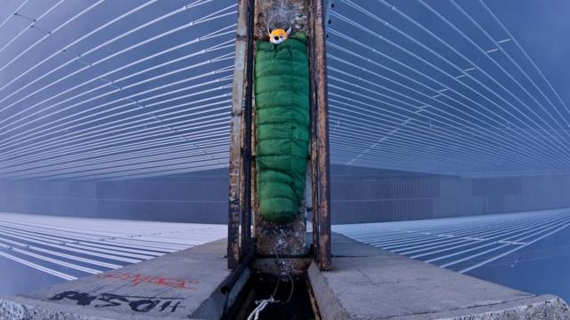 Explorador en saco de dormir en la parte alta de un puente