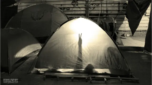 معتصم يرفع علامة النصر من داخل خيمة في ميدان التغيير بصنعاء - أمين الغابري 2011