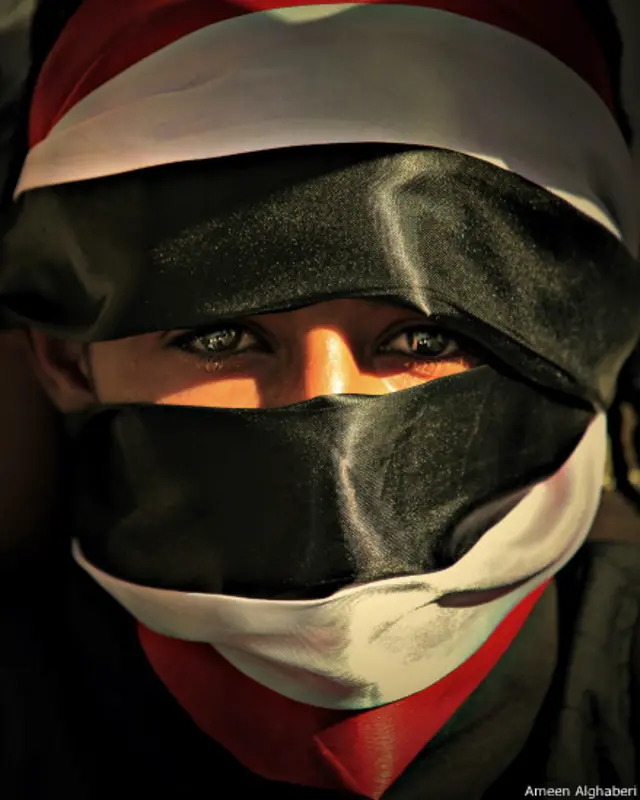 صورة لمتظاهر يغطي وجهه بعلم اليمن - أمين الغابري 2011