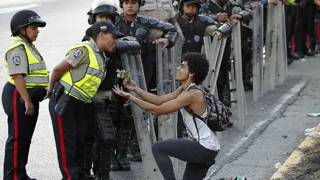 Manifestante ofrece una flor a mujer policía