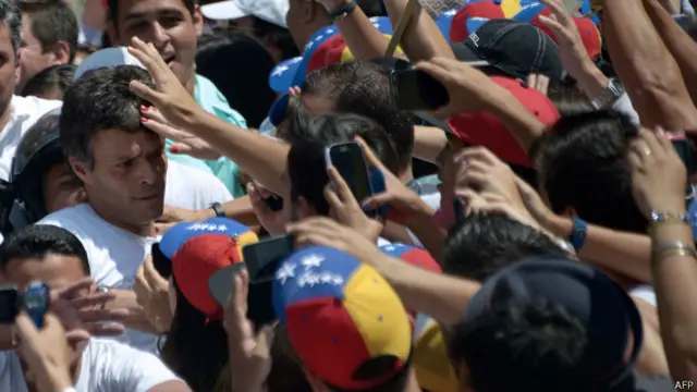 Leopoldo López (à esq.) cercado de manifestantes ao se entregar à polícia (AFP)