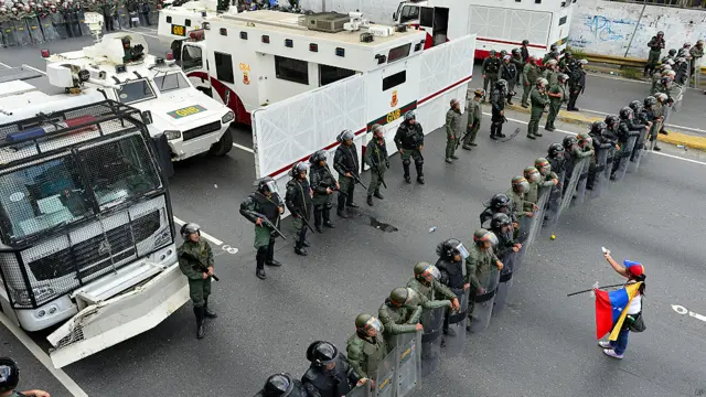 Una manifestante se para frente a efectivos de la Guardia Nacional Bolivariana.