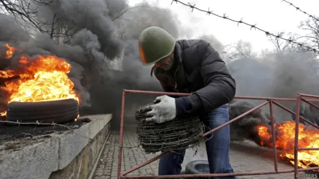 یکی از مخالفان برای جلوگیری از ورود پلیس اوکراین، در میدان استقلال سیم خاردار می‌کشد