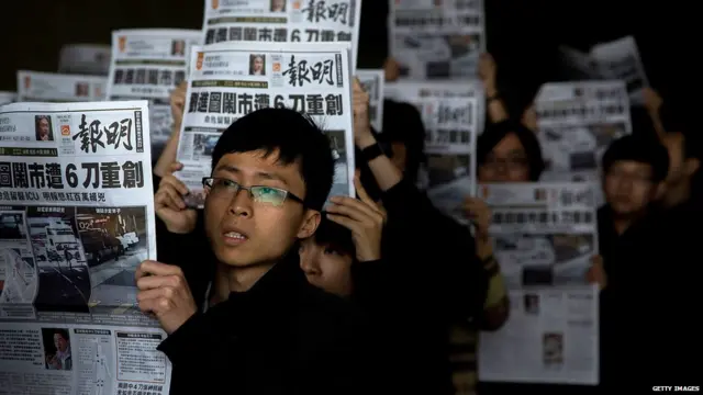 香港《明报》员工在报社外举起以刘进图遇袭为头版头条的报纸（27/2/2014）