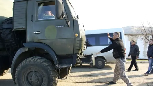 أُقيمت حواجز تفصل القرم عن أوكرانيا. وفي هذه الصورة، يقوم أحد سكان قرية بيريفالنوي الموالين للروس بمحاولة إيقاف شاحنة إمدادات يقودها أحد أفراد الخدمة الأوكرانيين.