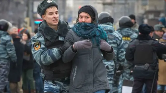 في روسيا، يعارض البعض قرار الرئيس بوتين بالتدخل العسكري في أوكرانيا. وفي الصورة، يعتقل أحد رجال الشرطة متظاهرة أثناء مظاهرة في موسكو ضد التدخل العسكري الروسي في القرم.