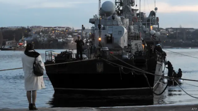 Mulher olha para navio ucraniano isolado na baía de Sevastopol (foto: AFP)