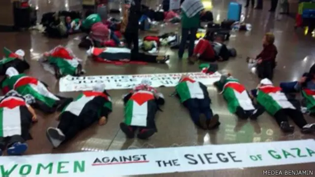 النسوة استلقين على أرض مطار القاهرة ولففن أجسادهن بأعلام فلسطين تعبيرا عن دعمهن للمرأة الفلسطينية في غزة.