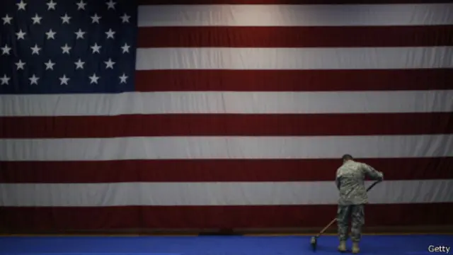 جندي أمريكي يكنس الأرض أمام العلم الأمريكي قبل استقبال جنود عائدين إلى أمريكا في فبراير 2014