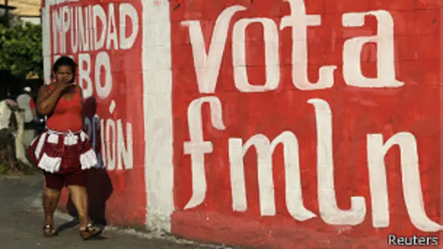 Mujer cruza por un cartel del FMLN en El Salvador.