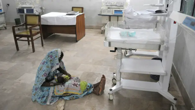 صوبہ سندھ کے ضلع تھرپارکر کے دارالحکومت مٹھی کے ڈسٹرکٹ ہسپتال میں ایک خاتون اپنی بچی کے ساتھ زمین پر بیٹھی ہیں۔ 