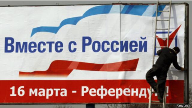 Рабочий вывешивает плакат (Симферополь, 12 марта 2014 г.)