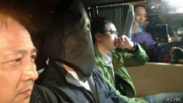 香港警方探员押解一名嫌疑人（中）到北角警署扣查（香港电台图片13/3/2014）