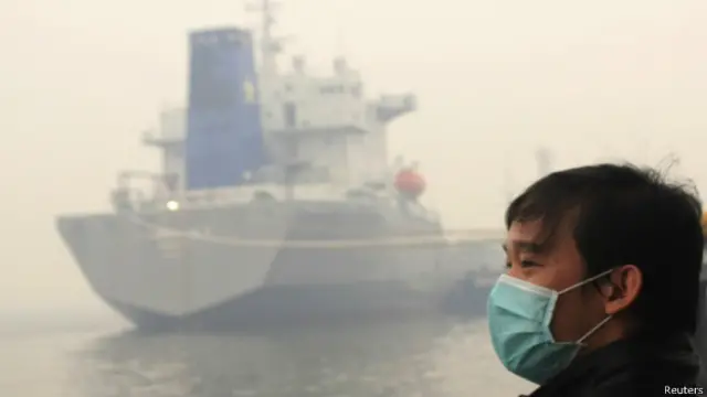 Seorang warga Kota Dumai, Riau mengenakan masker di pelabuhan kota itu.