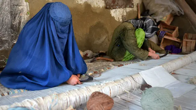 د خراسان په نامه افغان کډوالو کمپ کې چادرۍ لرونکې مېرمنې پر غالیو اوبدلو کې ونډه لري.