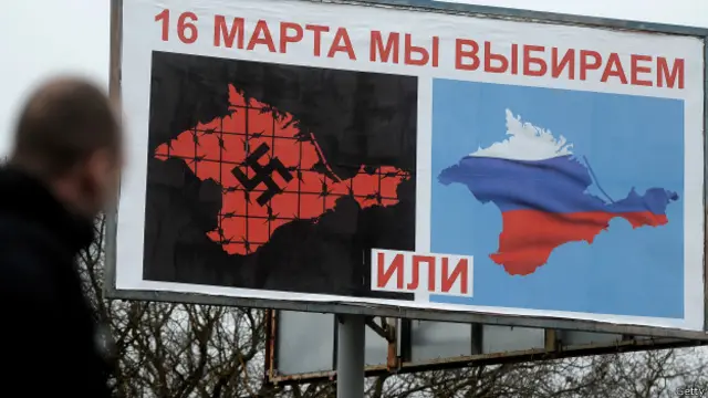 Cartaz na Crimeia mostra mapas da região pintado com a suástica nazista ou com cores russas, e dizeres: 'Escolheremos no dia 16' (Getty)