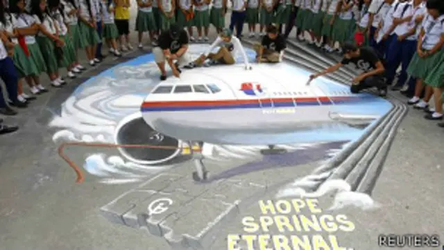 Jóvenes escriben mensajes de buena voluntad junto al dibujo de un avión en el suelo 