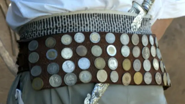Argentinian cowboy wearing an ornamental belt adorned with coins and holding a knife