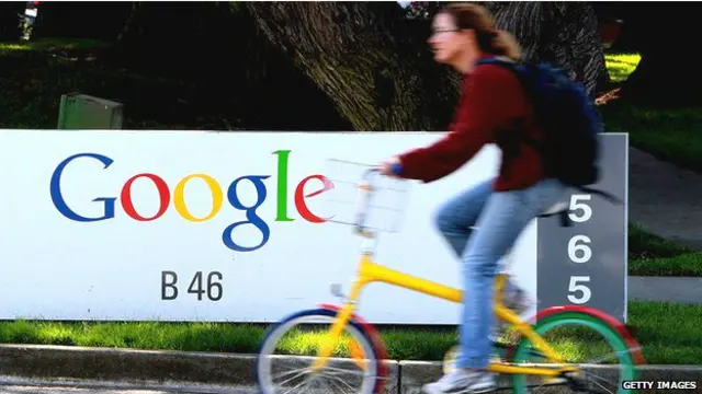 Mujer pasa en bicicleta frente a aviso de Google