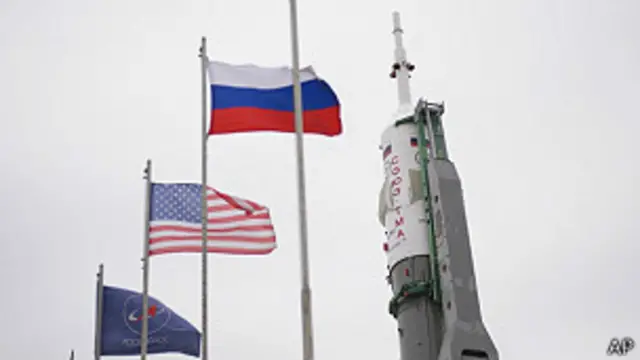banderas de Rusia y EEUU al lado de un Soyuz
