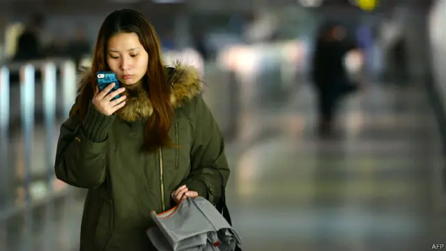 चीन में मोबाइल का इस्तेमाल करती युवती
