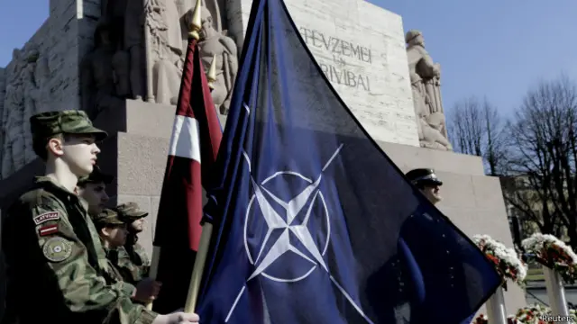 नाटो का झंडा थामे लातविया का सैनिक