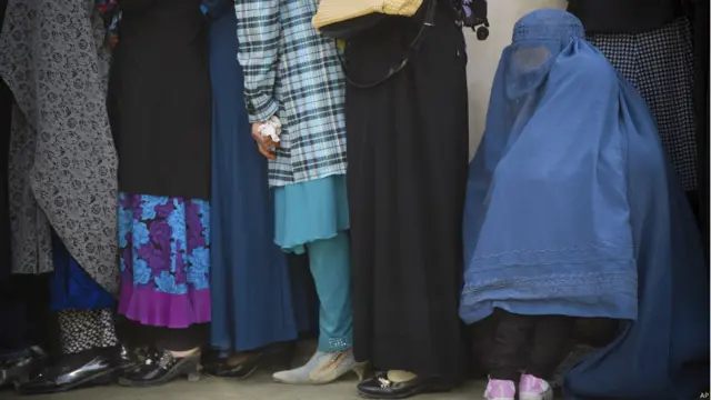 کابل میں خواتین آنے والے صدارتی انتخابات کے لیے ووٹ کے اندراج کے لیے جمع ہیں جہاں ایک بچہ اپنی ماں کے برقعے میں چھپنے کی کوشش کر رہا ہے۔