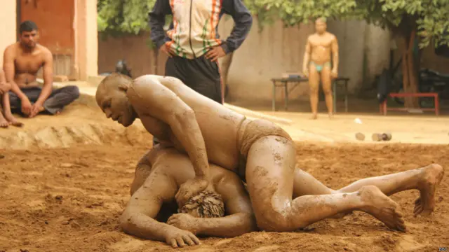 अखाड़े में कुश्ती लड़ते दो पहलवान