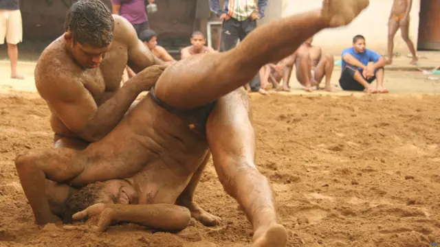 अखाड़े में कुश्ती लड़ते दो पहलवान