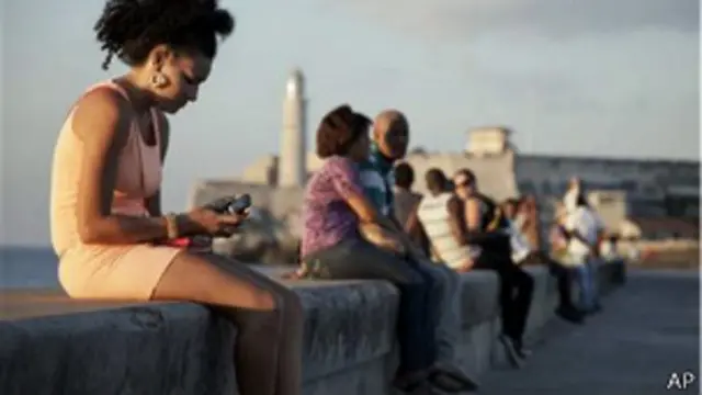 Una cubana mira el movil en el malecón