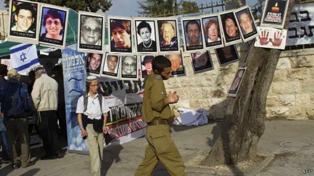 Израильский солдат идет мимо плакатов с изображением жертв палестинских заключенных