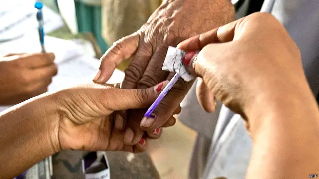 उत्तर प्रदेश के मुजफ्फरनगर में मतदाता को स्याही लगाती मतदान कर्मी