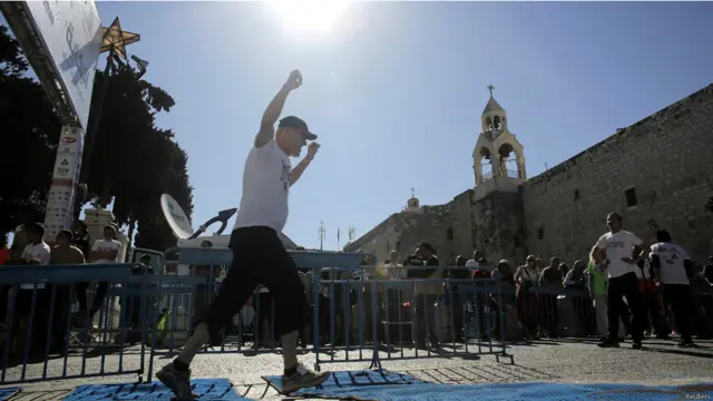 یو ګډون کوونکی د بیت لحم المهد کلیسا مخې ته ځغاستي. 