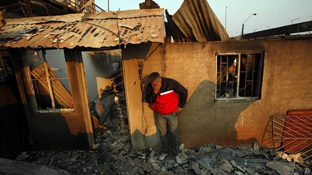 hombre solloza frente a su casa destruida por el fuego en Valparaiso, Chile