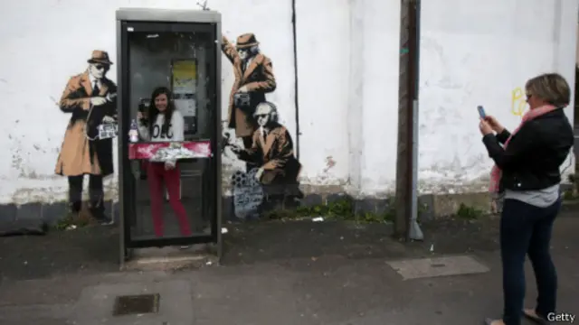 班克西的“间谍电话亭”表现几个男人围着一个电话亭搞“窃听”。