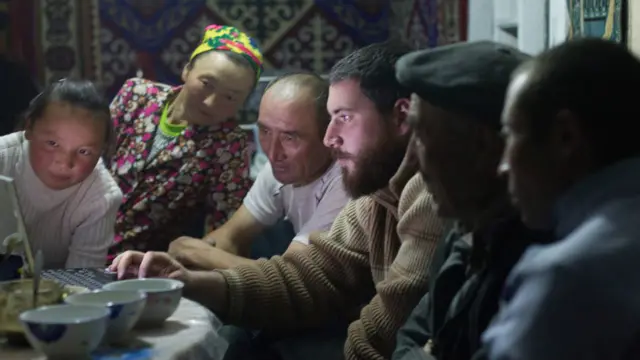 Свиденский қўл компютеридаги суратларни Ашол-Паннинг оила аъзоларига кўрсатади.