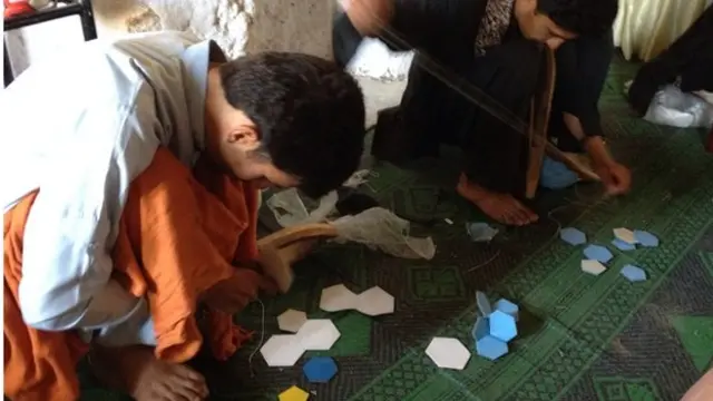 مردان جوان در حال دوختن توپ فوتبال در کارگاهی که توسط ارتش پاکستان ساخته شده