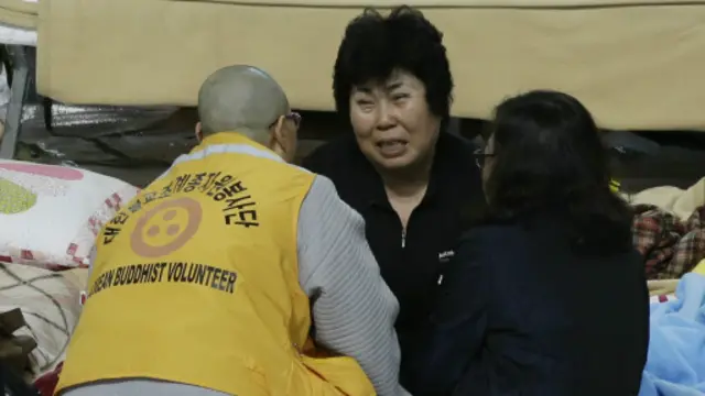 راهب بوذي يهدئ من روع إحدى قريبات ضحايا العبارة.